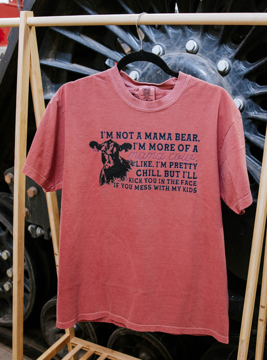 Pink t-shirt with text on a wooden rack in front of large wheels.
