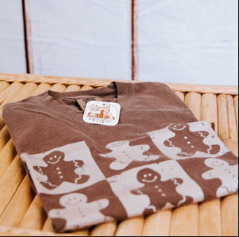 Brown sweater with gingerbread man pattern on a wooden surface with a snowy window background