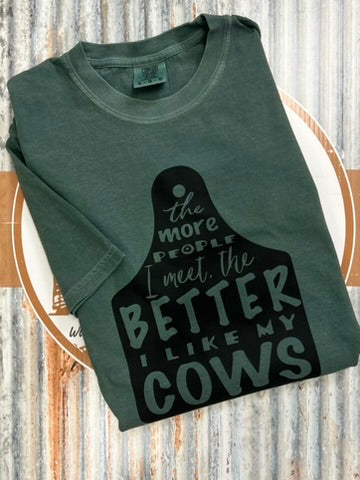 Green t-shirt with black graphic and text on a wooden surface