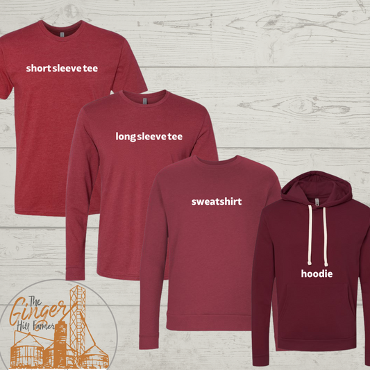 Collection of red clothing items labeled 'shortsleeve tee', 'longsleeve tee', 'sweatshirt', and 'hoodie' on a wooden background.