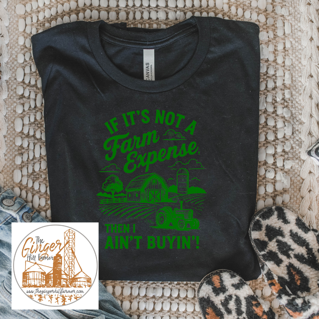 Black t-shirt with green text and graphics on a textured surface, featuring a small inset of a logo.