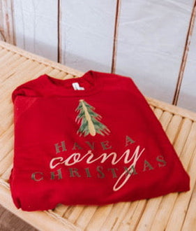Red Christmas-themed sweatshirt with a tree design and text on a wooden surface.