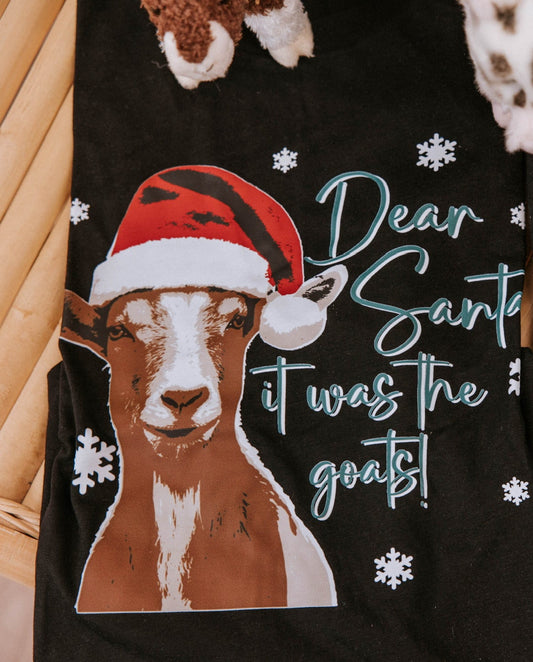 Black t-shirt with Christmas-themed animal graphics and text on a wooden surface.