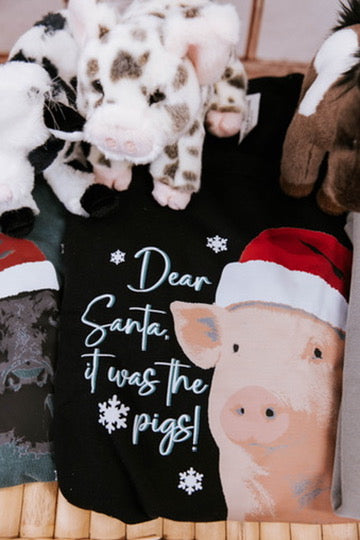 Black shirt with a pig illustration and text 'Dear Santa, it was the pigs!' surrounded by plush toys.