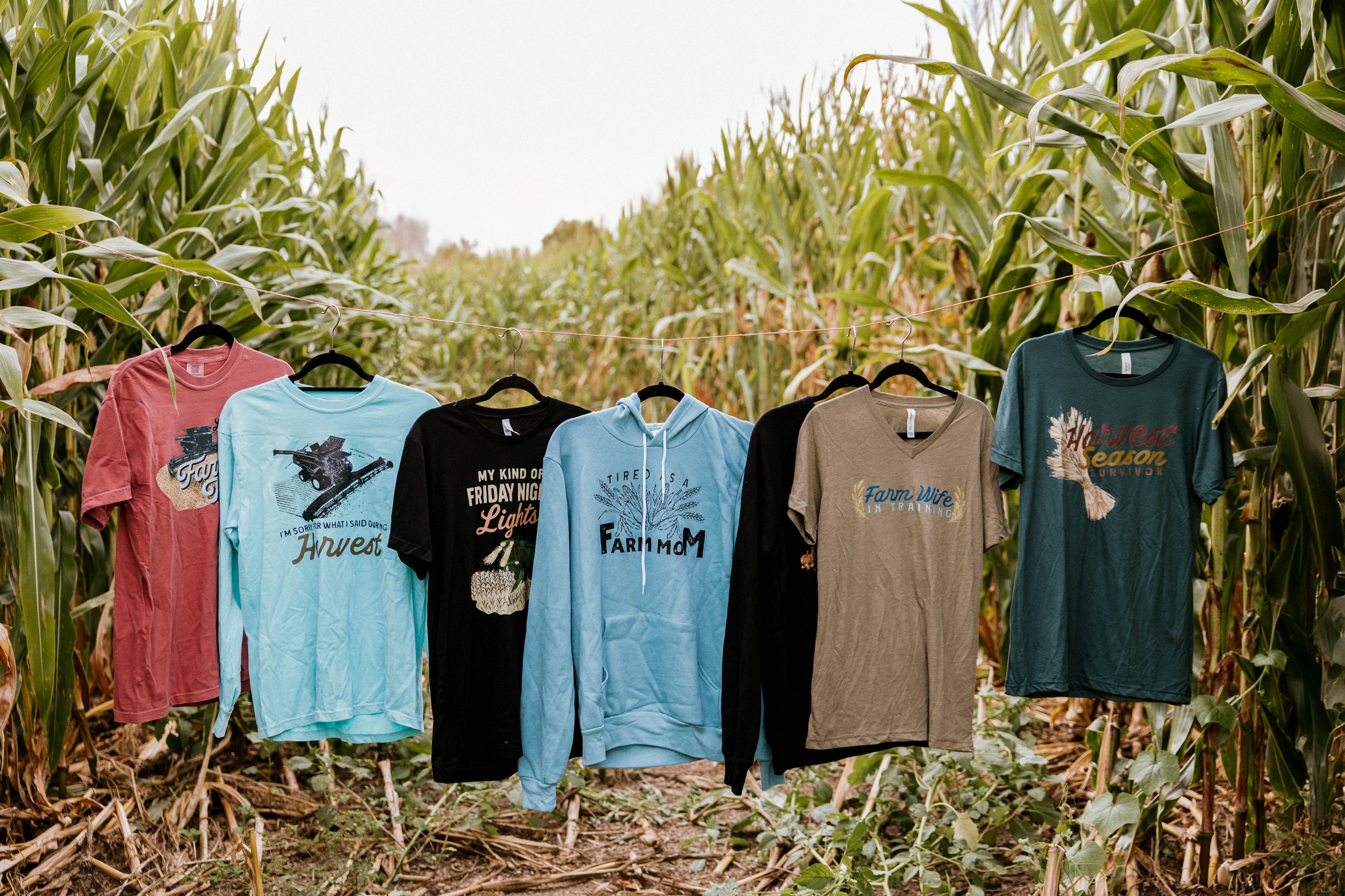T shirts with graphics hanging in a field of corn