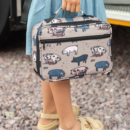 Person holding a patterned lunch bag with animal designs on a gravel surface