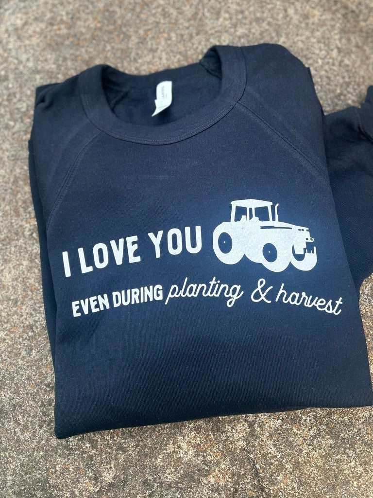 Folded black sweatshirt with white text and tractor graphic on a textured surface