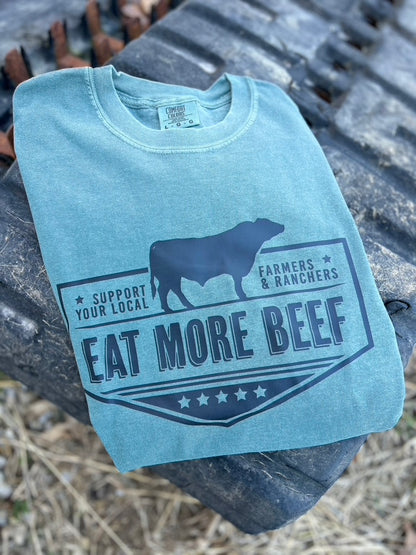 green tee with a cow silhouette and text on a metal surface