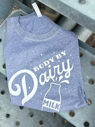 Gray t-shirt with 'Body by Dairy Milk' text on a metal surface