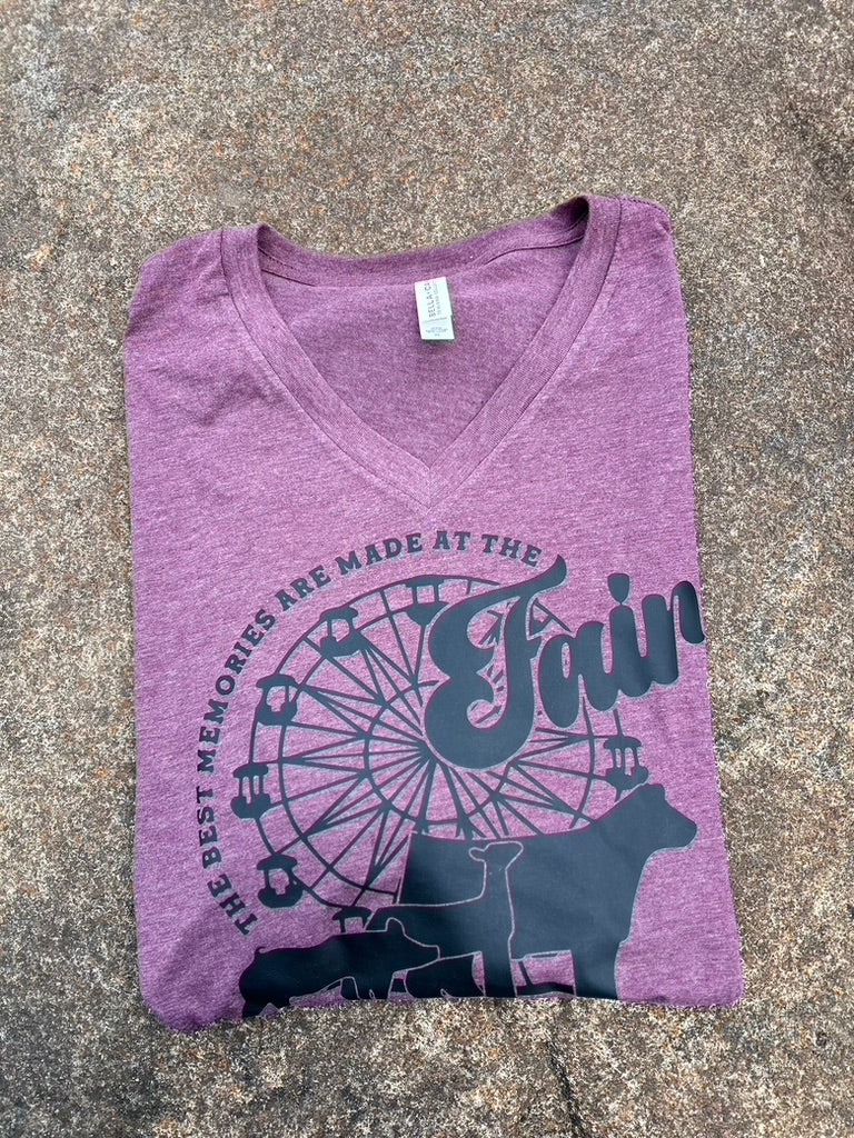 Purple t-shirt with fairground design and text on a gray surface