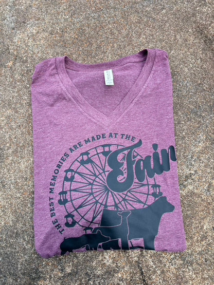 Purple t-shirt with fairground design and text on a gray surface