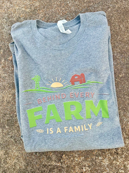 Folded grey t-shirt with a farm-themed graphic and text on a concrete surface