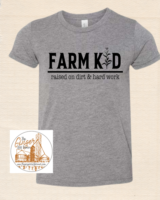 Gray t-shirt with 'Farm Kid, raised on dirt & hard work' text on a beige background
