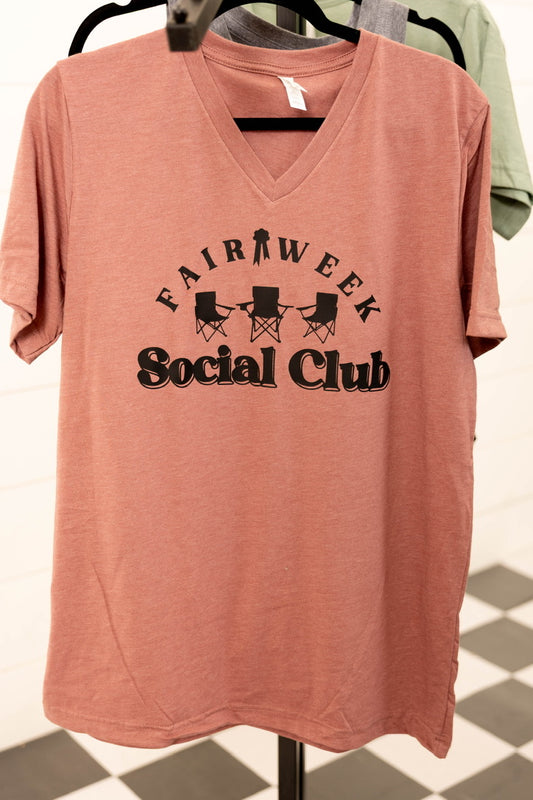 Pink t-shirt with 'Fairview Social Club' text on a hanger against a checkered floor background