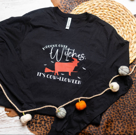 Black t-shirt with Halloween design on a wooden surface with decorative elements.
