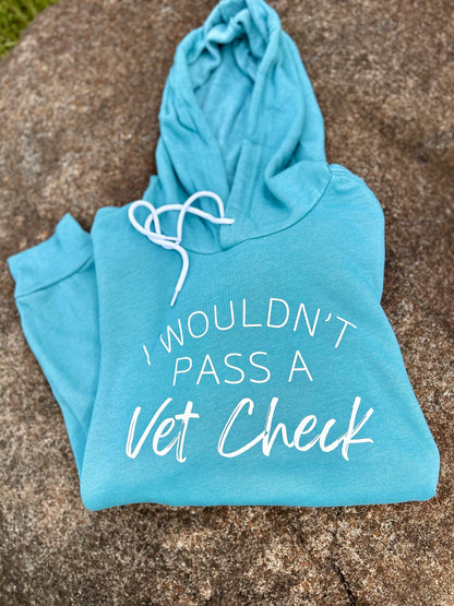 Blue hoodie with 'I Wouldn't Pass a Vet Check' text on a stone surface