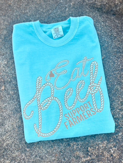 Light blue t-shirt with 'Eat Beef Support Farmers' text on a textured surface