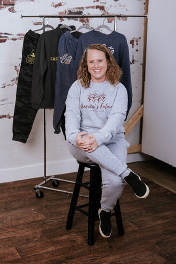 model sitting in front of rack of clothes with white walls and wood floors
