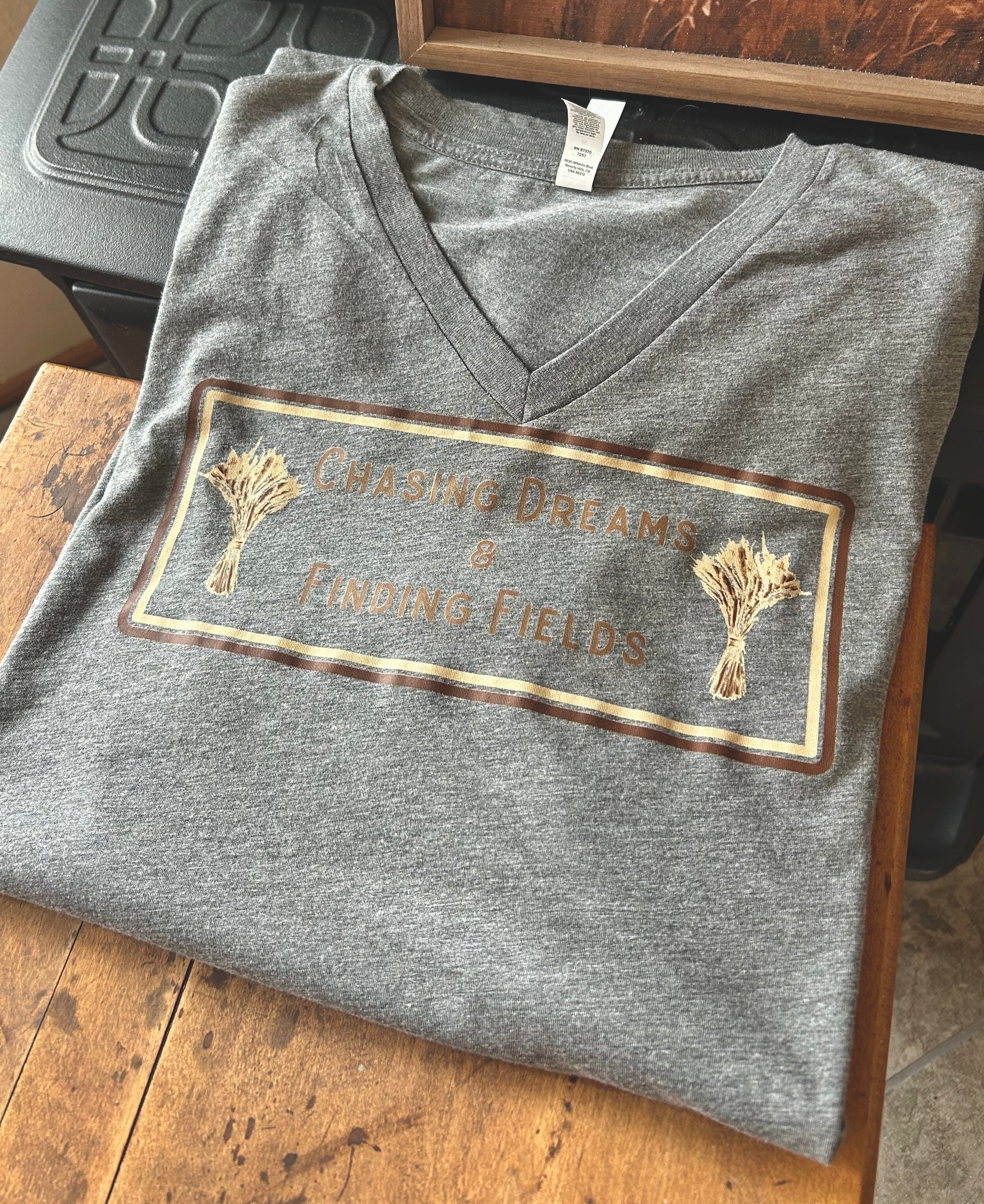 Folded gray V-neck shirt with a printed design on a wooden surface