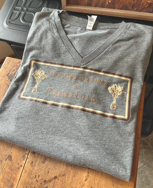 Folded gray V-neck shirt with a printed design on a wooden surface