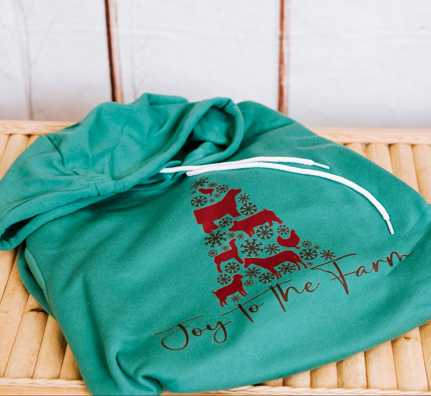 Green shirt with red and brown design on a wooden surface with a tiled wall background