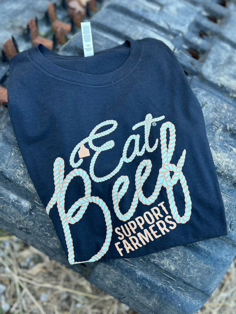 black t-shirt with 'Eat Beef Support Farmers' text on a stone surface