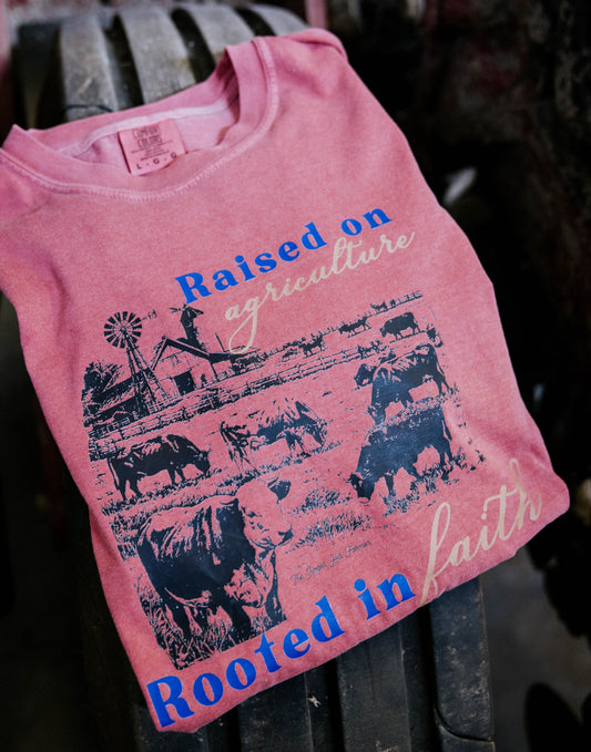 Pink t-shirt with agricultural graphics and text on a metal surface