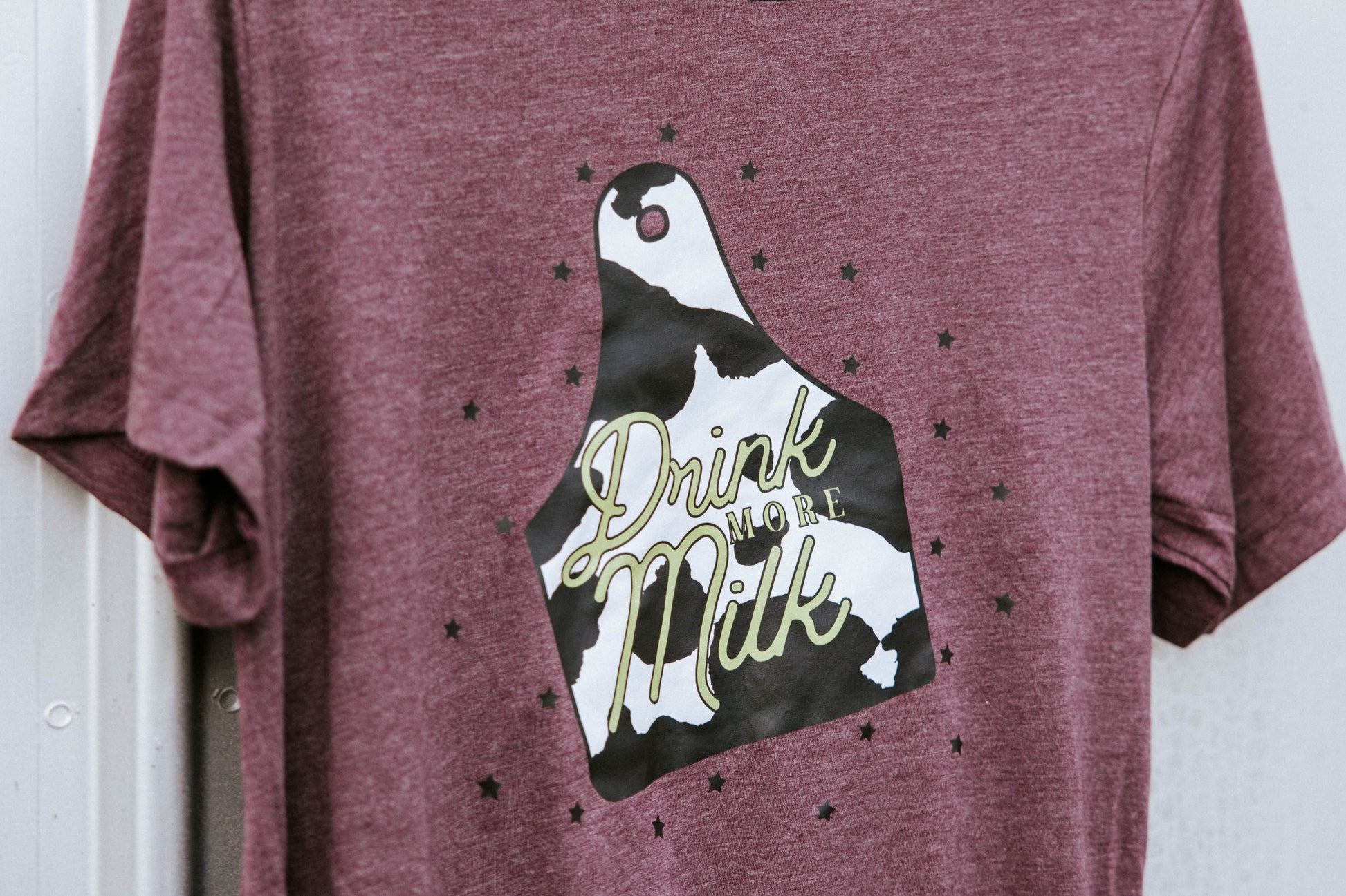 Close up of cattle tag graphic on a maroon tee