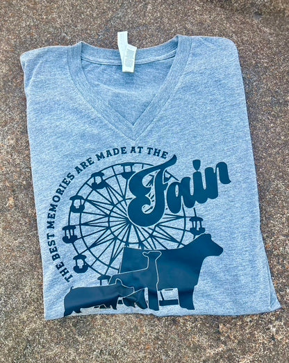 Folded grey t-shirt with fair-themed design on a textured surface