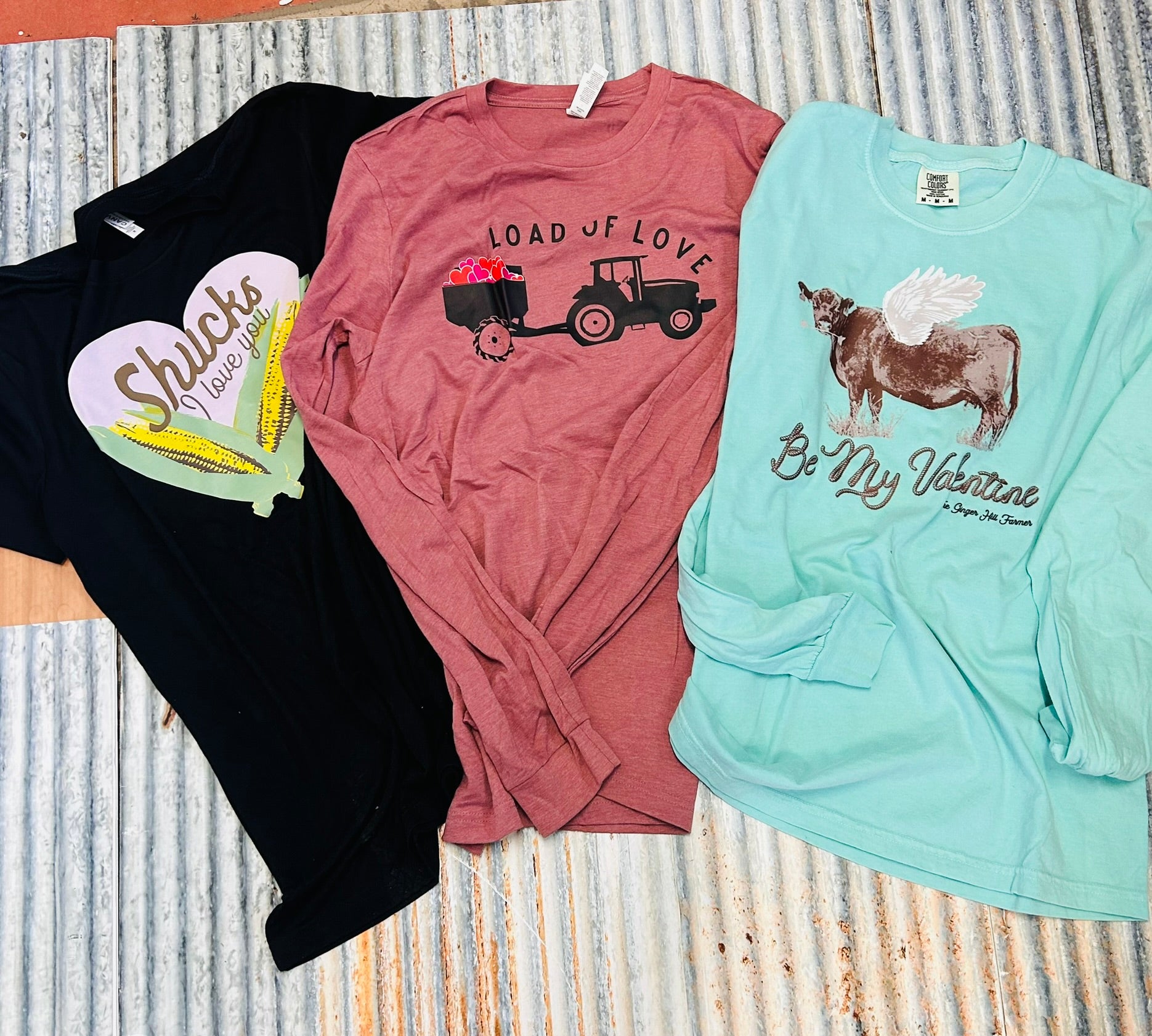 Three long-sleeve shirts with different designs on a textured surface