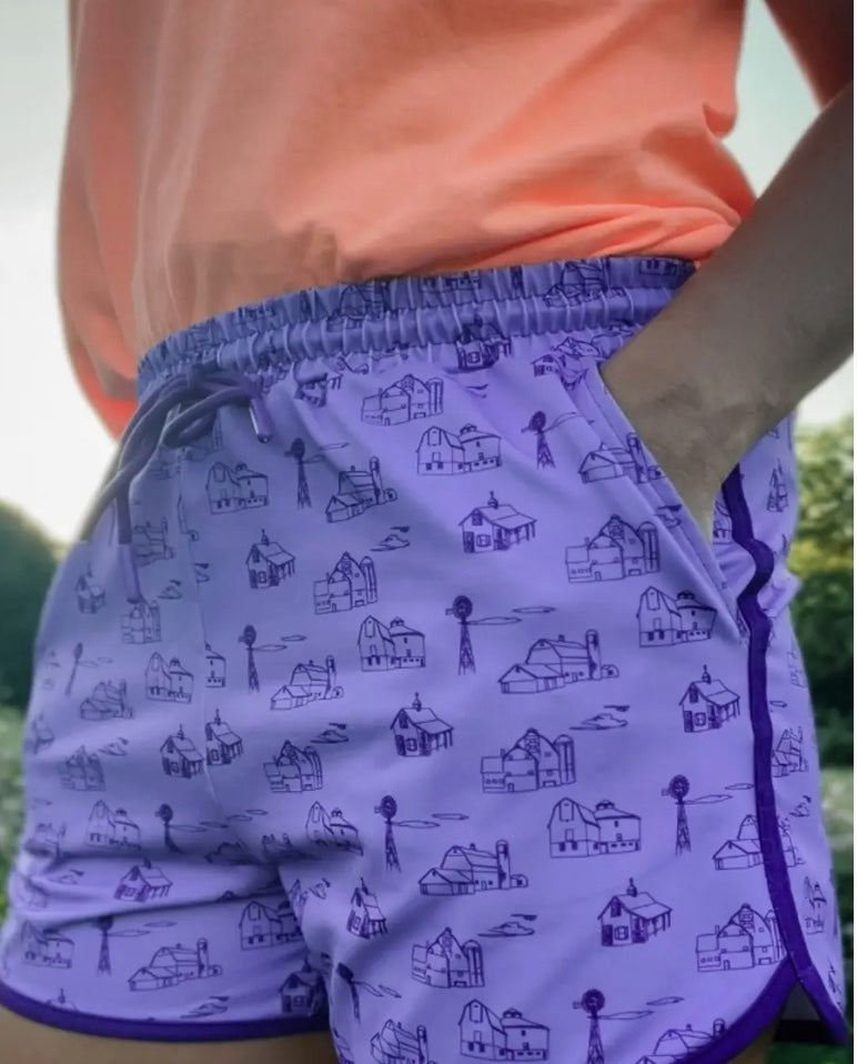 Purple shorts with a pattern of small buildings and windmills worn by a person.