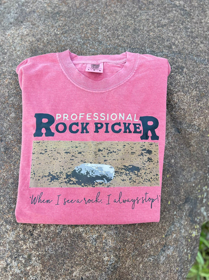 Pink t-shirt with 'Professional Rock Picker' text on a stone surface
