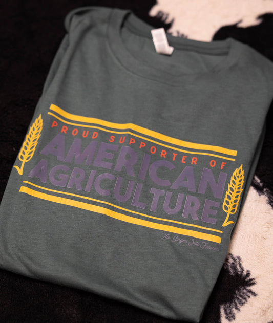 Green t-shirt with 'Proud Supporter of American Agriculture' text on a dark surface