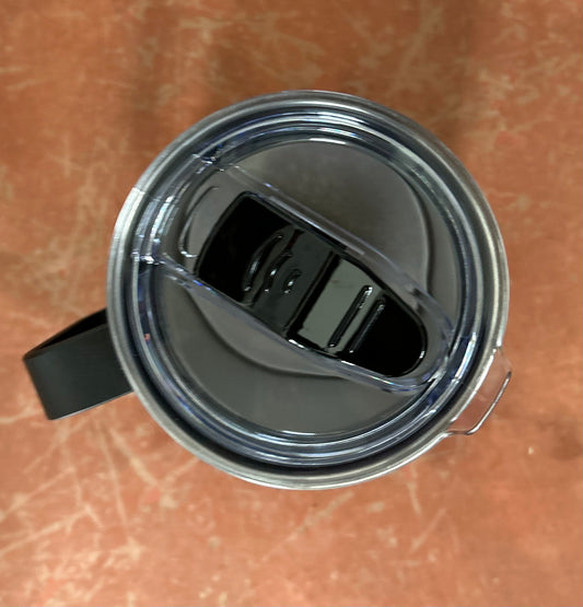 Close-up of a metal mug with a black handle on a brown surface