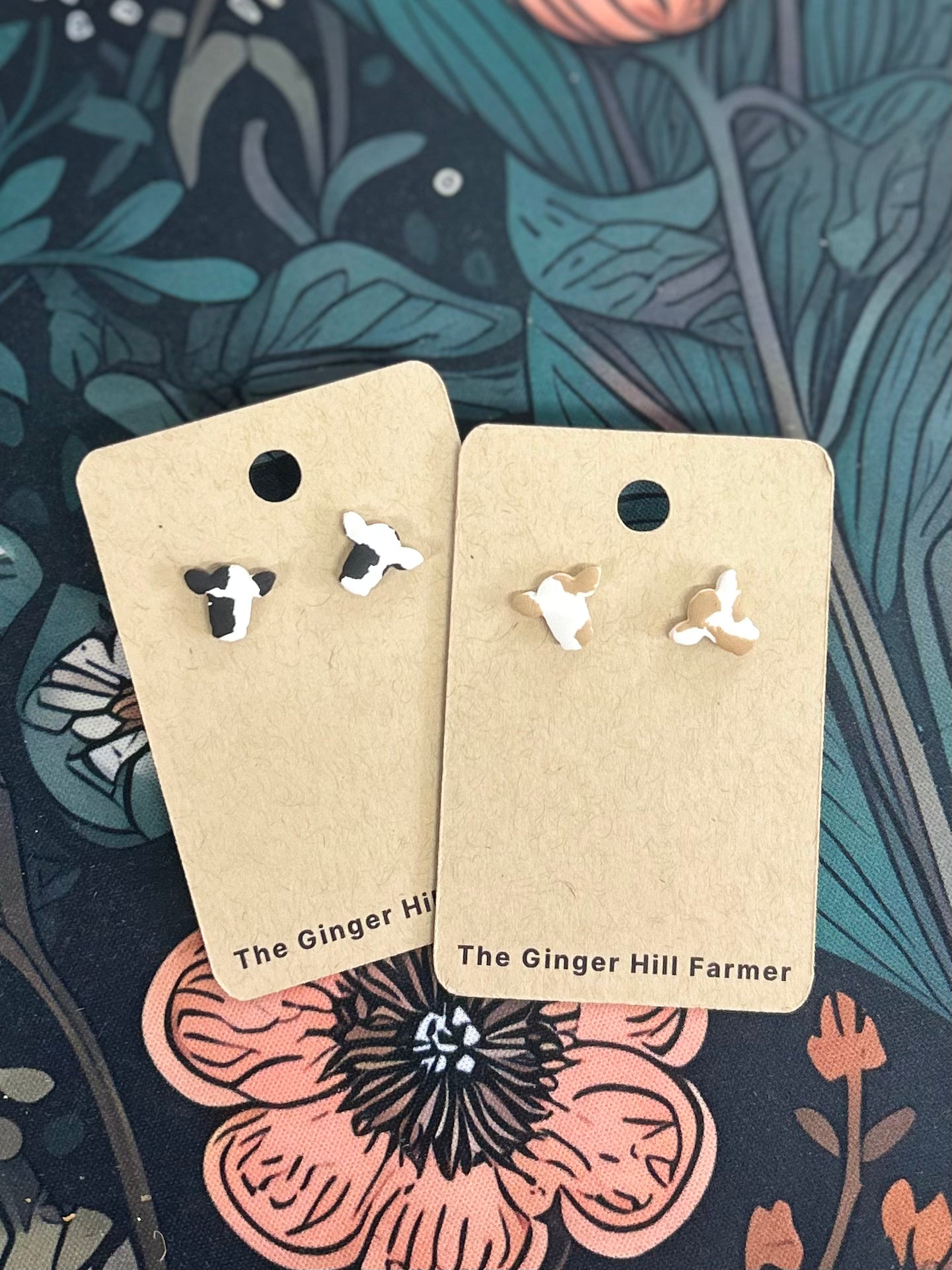 two pairs of cow earrings on brown cardstock