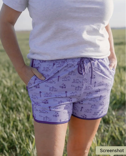 Person wearing purple patterned shorts and a white shirt in an outdoor setting