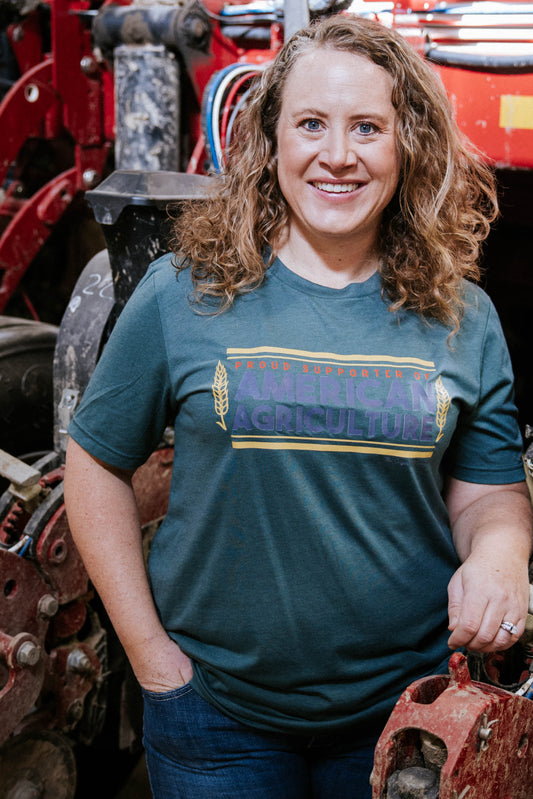 Person standing in a mechanical or industrial setting wearing a green t-shirt with a colorful design.