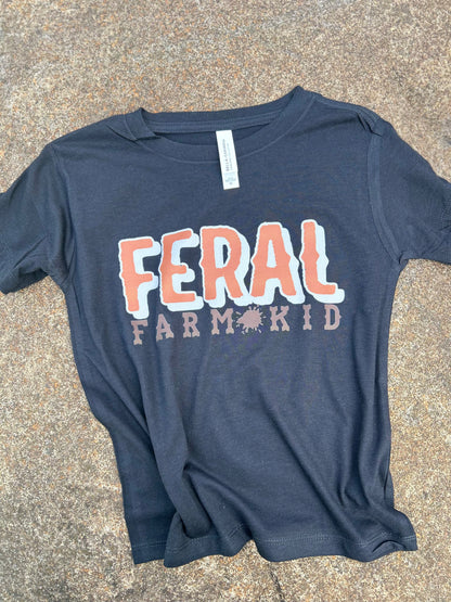 black t-shirt with 'FERAL FARM KID' text on a concrete surface