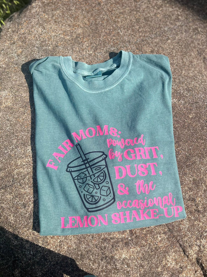 Light blue t-shirt with pink text and graphic on a concrete surface
