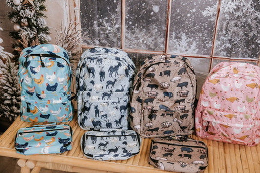 Set of animal-patterned backpacks and pouches on a wooden surface with a tiled wall background.
