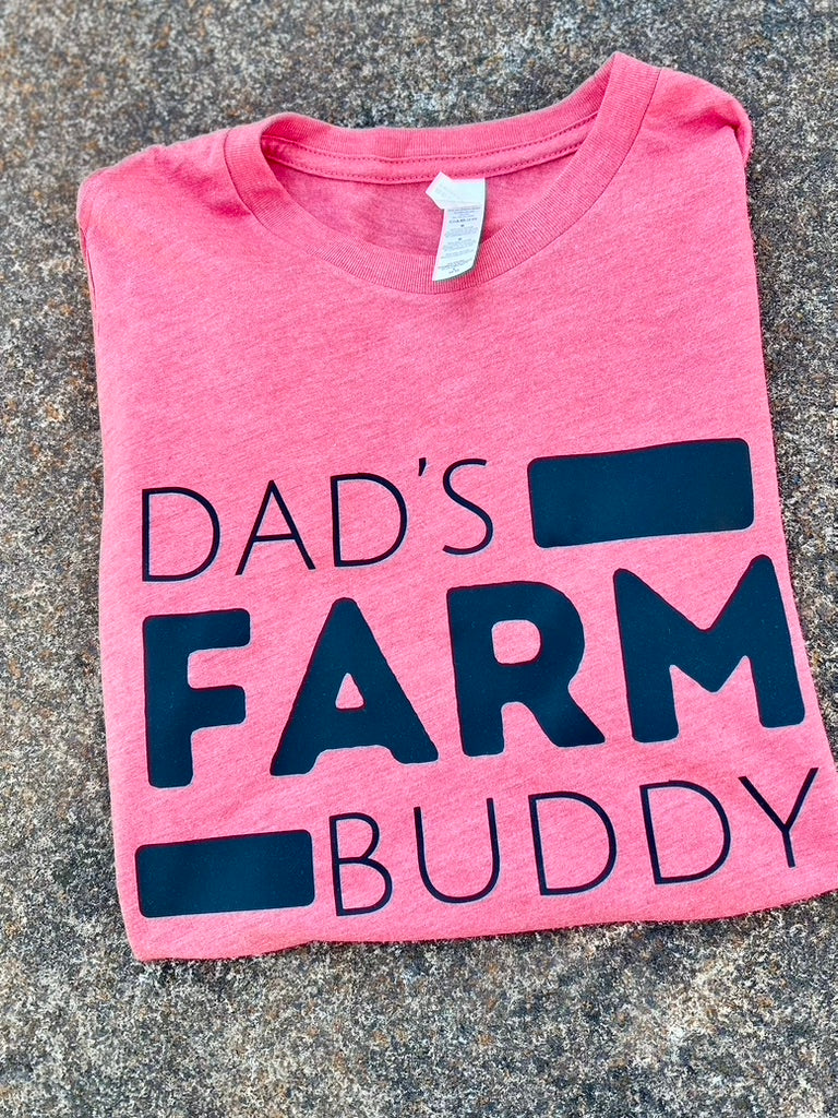 red t-shirt with 'Dad's Farm Buddy' text on a concrete surface