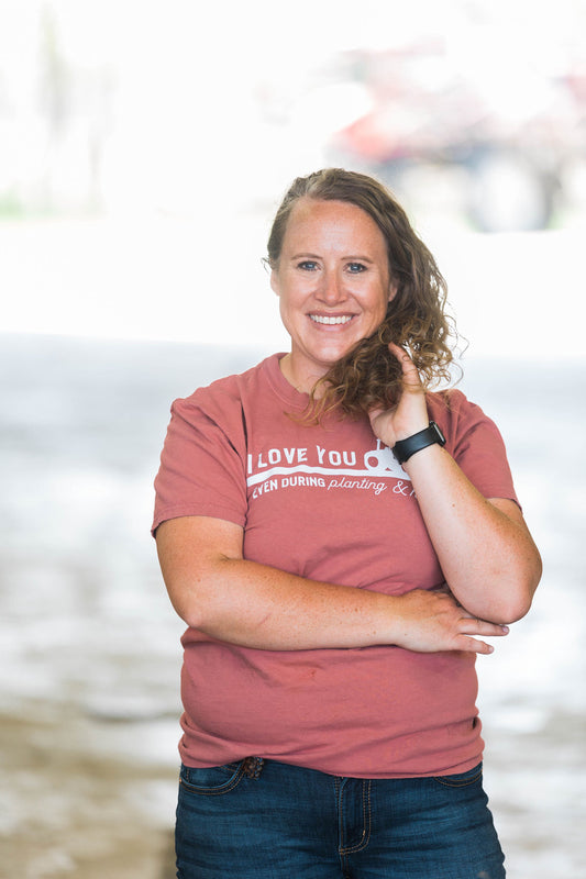 Woman wearing a red t-shirt with text, standing outdoors with a blurred background
