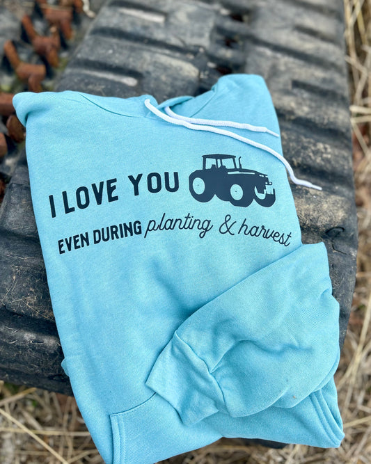 Light blue hoodie with text and tractor graphic on a rustic background