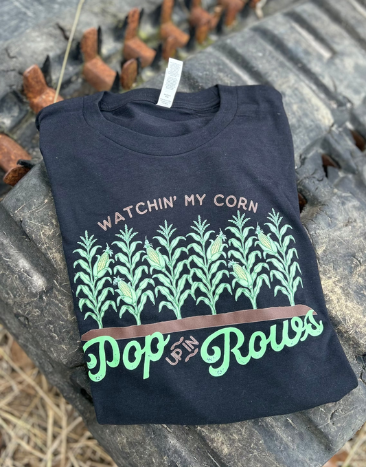Black t-shirt with corn plant design and text on a rustic metal surface