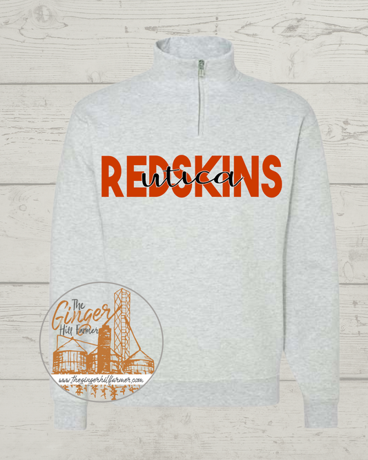 Gray sweatshirt with 'REDSKINS utica' text on a wooden background