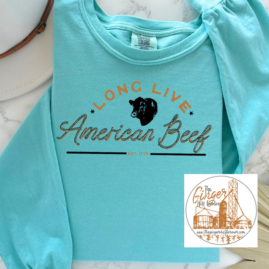 Turquoise sweatshirt with 'Long Live American Beef' text and bear graphic on a marble surface.