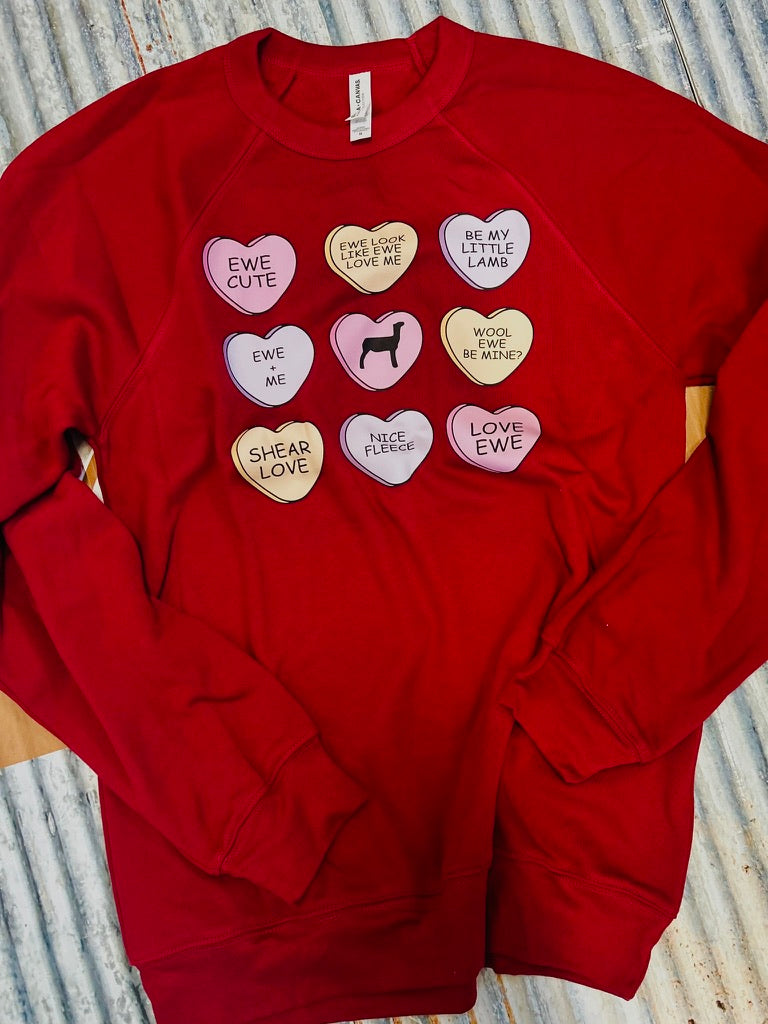 Red sweatshirt with heart-shaped patches on a textured surface