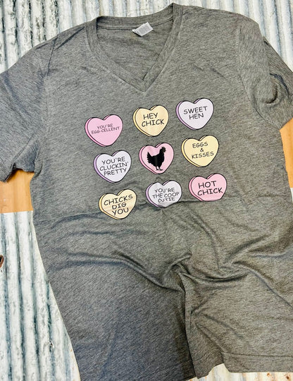 Gray t-shirt with colorful heart-shaped pins on a wooden surface