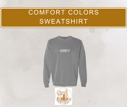 Gray sweatshirt with 'GREY' text on a textured beige background, featuring a brand logo at the bottom.