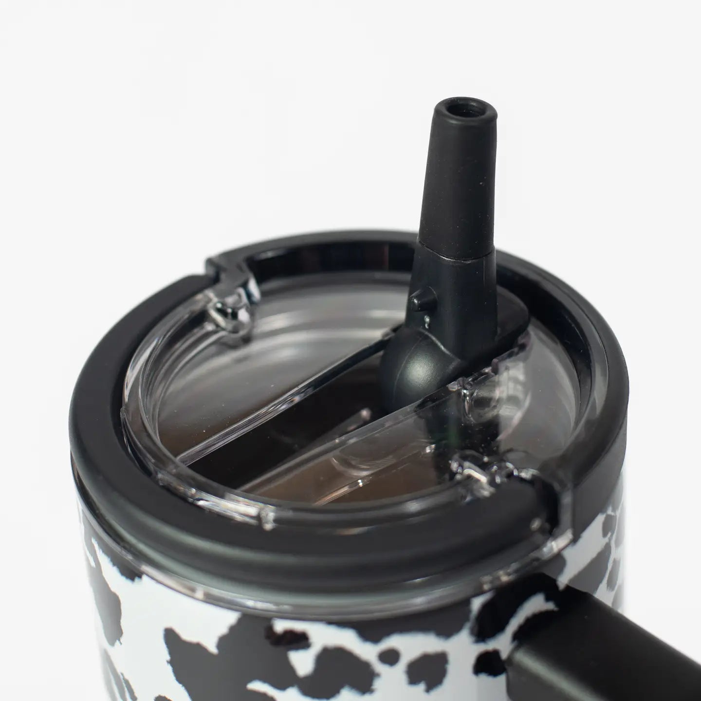 Close-up of a black lid with a straw on a clear cup against a white background